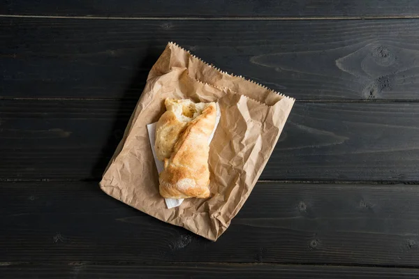 Вид сверху кондитерского булочка на бумажном пакете на деревянном столе — стоковое фото
