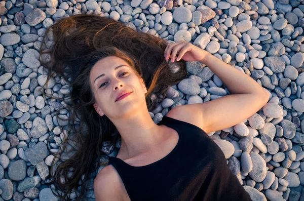 小石で覆われてビーチに横たわる女 — ストック写真