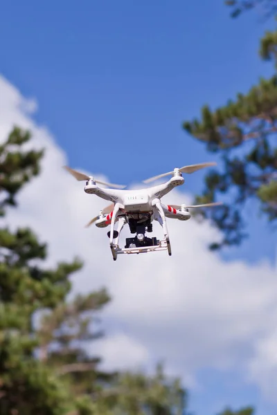 Beyaz dron ağaçlar arka plan üzerinde uçan — Stok fotoğraf
