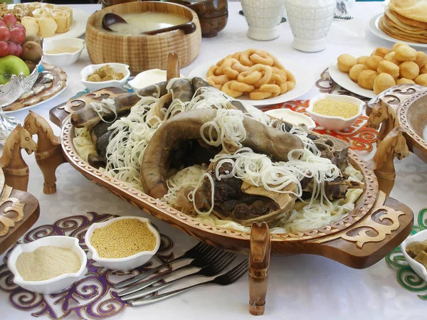 Beshbarmak - plato nacional kazajo en una bandeja de madera tallada. Mesa festiva Imágenes de stock libres de derechos
