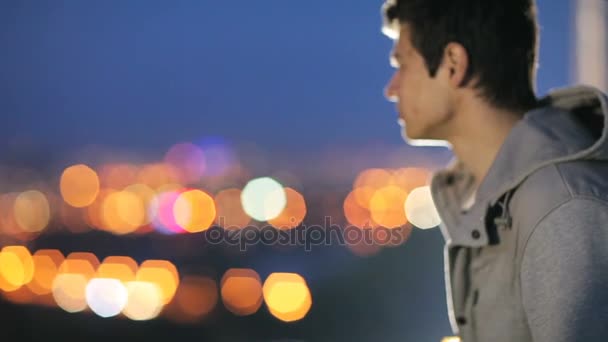 Een jonge jongen kijkt naar de stad van de nacht — Stockvideo