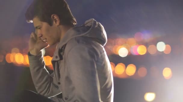 Young man speaks on cellphone on the background of the city at night — Stock Video