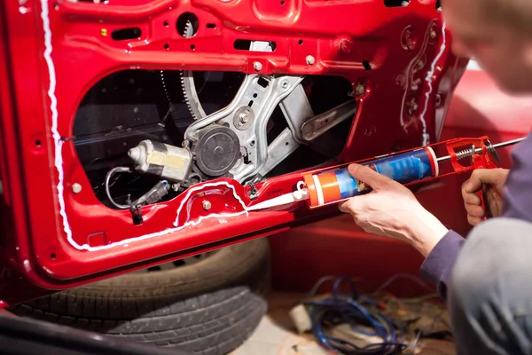 A man applies sealant to the car door — Stock Photo, Image