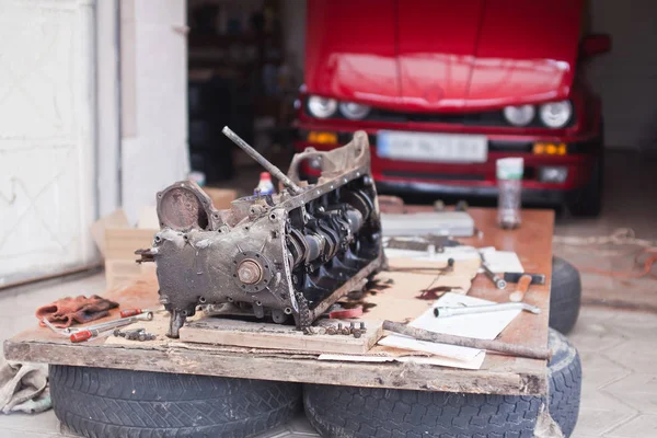 Araba kırmızı arka plan üzerinde yatıyor motoru tamir — Stok fotoğraf