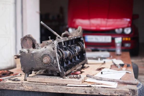Ремонт двигателя, который лежит на фоне красного автомобиля — стоковое фото