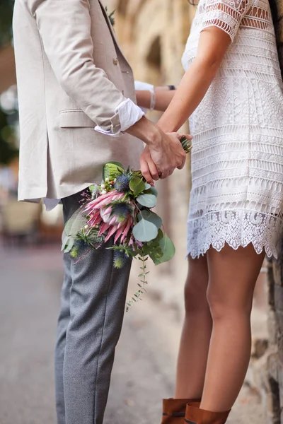 A guy holding a girl by the hand with a bouquet of flowers — Stock Photo, Image