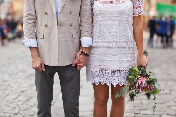 A guy holding a girl by the hand with a bouquet of flowers — Stock Photo, Image