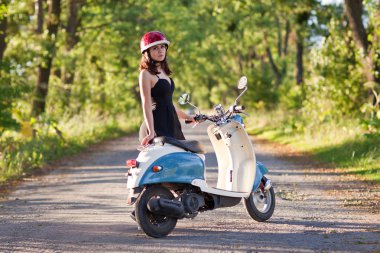 Bir scooter üzerinde köy yolunda bir kızla