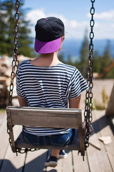 Bir genç kız dağlara bakan salıncakta sürme