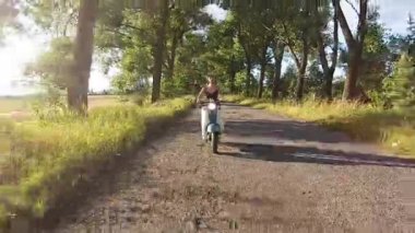 Bir kız bir ara sokakta ağaçları ile üzerinde bir motosiklet sürme