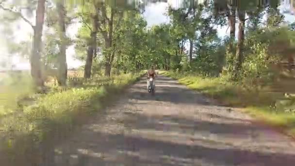 Uma menina está montando um ciclomotor em um beco com árvores — Vídeo de Stock