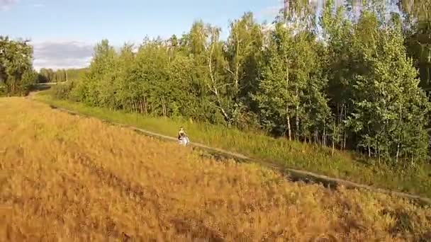 En tjej rider en skoter på en landsväg — Stockvideo