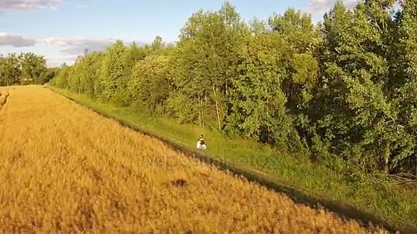 En tjej rider en skoter på en landsväg — Stockvideo