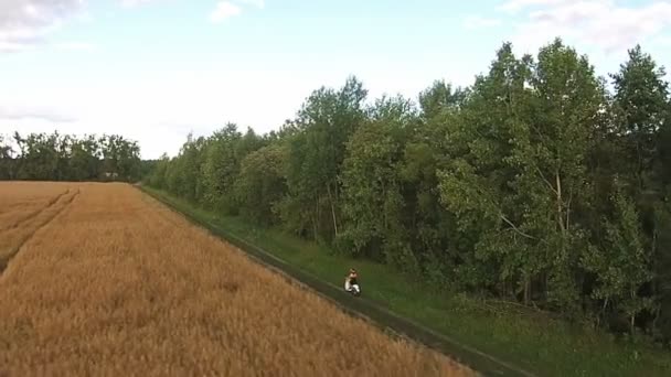 Uma menina montando uma scooter em uma estrada de campo — Vídeo de Stock