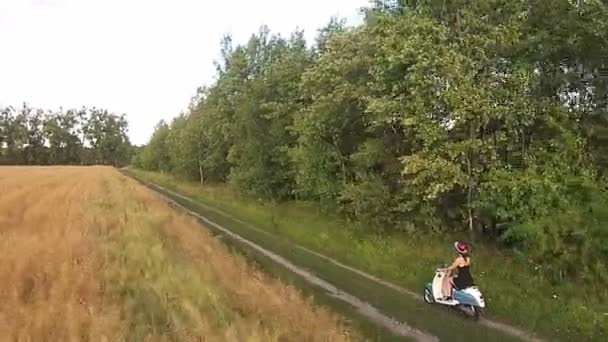Uma menina montando uma scooter em uma estrada de campo — Vídeo de Stock