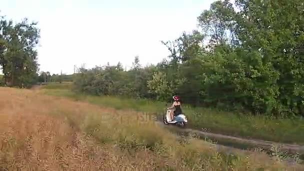 Ein Mädchen auf einem Motorroller auf einer Landstraße — Stockvideo