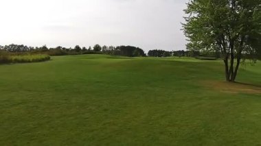 Bir dron yeşil bir golf sahası üzerinde uçar