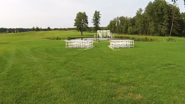 Um drone voa sobre um campo de golfe verde com arco de casamento — Vídeo de Stock