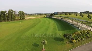 Bina ile yeşil bir golf sahası üzerinde bir uçak uçar