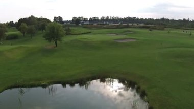 Göl ile yeşil bir golf sahası üzerinde bir uçak uçar