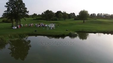 Bir dron yeşil bir golf sahası üzerinde uçar. Düğün töreni