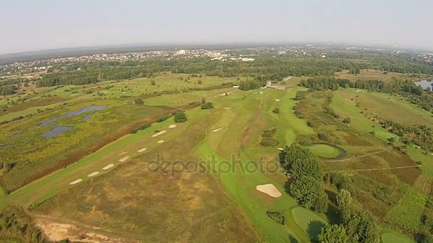 Беспилотник летит над зеленым полем для гольфа с озером — стоковое видео