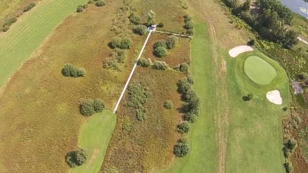 Un dron vuela sobre un campo de golf verde con lago — Vídeo de stock