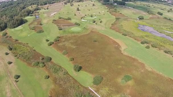 Un dron vuela sobre un campo de golf verde con lago — Vídeos de Stock