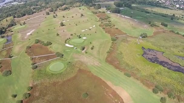 En drönare flyger över en grön golfbana med sjö — Stockvideo
