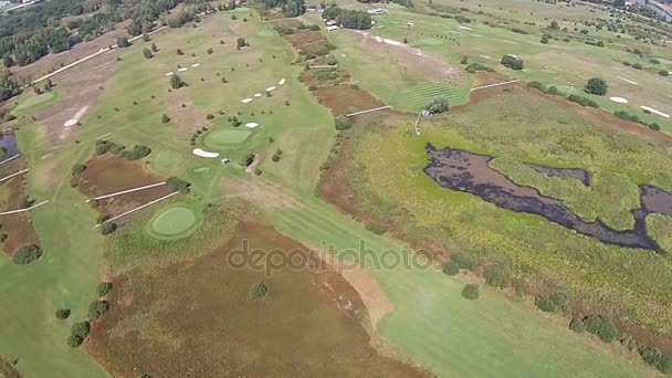 Een drone vliegt over een groene golfbaan met huwelijksboog — Stockvideo