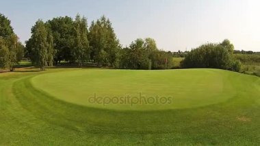 Yeşil golf sahası yukarıda bayrağı ile iyi üzerinden bir uçak uçar