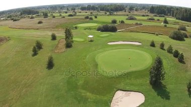 Yeşil golf sahası yukarıda bayrağı ile iyi üzerinden bir uçak uçar
