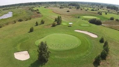 Yeşil golf sahası yukarıda bayrağı ile iyi üzerinden bir uçak uçar