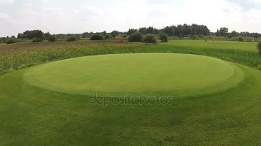 Yeşil golf sahası yukarıda bayrağı ile iyi üzerinden bir uçak uçar