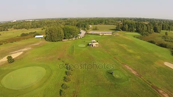 Un drone vola sopra un campo da golf verde con costruzione di golf club — Video Stock