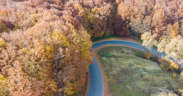 Luftaufnahme einer Straße in den Bergen mit Serpentinen durch die roten Bäume — Stockfoto