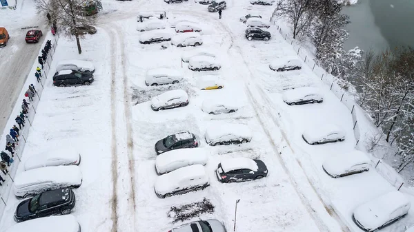 Aerila view of snow-covered cars stand in the parking lot on a winter day