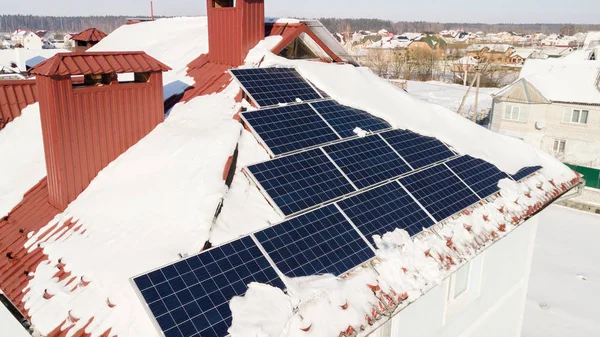 在冬天的大雪之后, 房子屋顶上的太阳能电池板 图库图片
