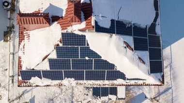 Kış aylarında yoğun bir kar yağışı sonra evin çatısında güneş panelleri. Yenilenebilir enerji üretim modülleri