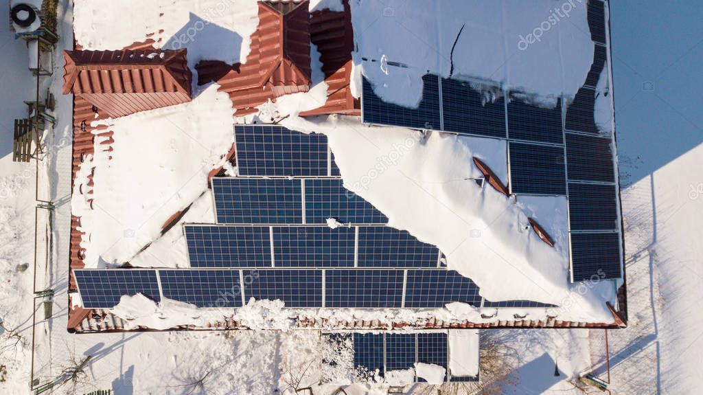 Solar panels on the roof of the house after a heavy snowfall in the winter. Renewable energy production modules