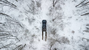 Aerial view on SUV 6x6 that rides by winter road in snow-covered forest clipart