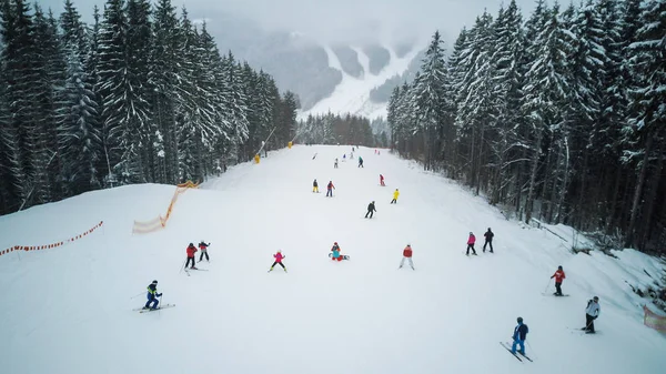Lyžaři a snowboardisté jít dolů na svahu v lyžařském středisku Bukovel, Ukrajina — Stock fotografie