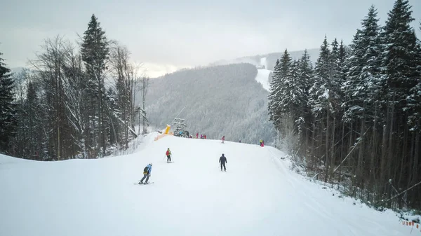 Esquiadores y snowboarders bajan por la pista en una estación de esquí Bukovel, Ucrania — Foto de Stock