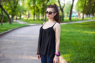 Genç bir kız parkta yürürken kameraya benziyor