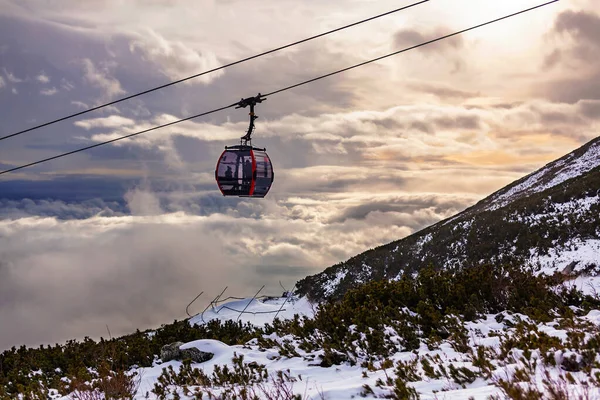 Kabelbaancabine boven de wolken bij zonsondergang — Stockfoto