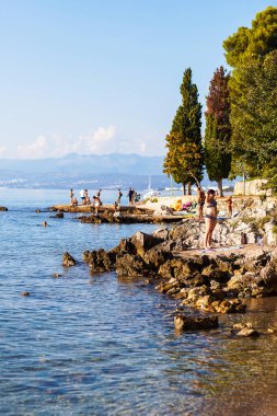 Njivice, Hırvatistan - 12 Nisan 2019: Yaşlılar kayalıklardaki deniz kıyısında dinleniyor.