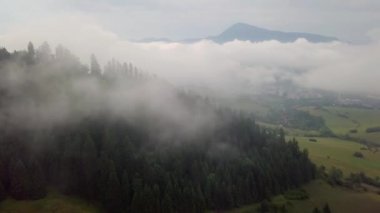 Alçak Tatra 'daki sisli havada sabah dağları manzarası ve arka planda şehir