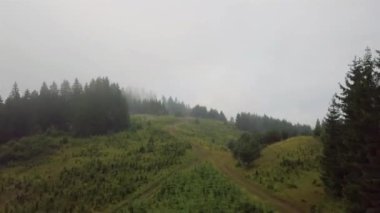 Sabah sisi boyunca yükselen ve arka planda şehir olan bir dağ yolunun havadan görüntüsü.
