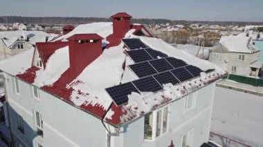 Kışın şiddetli bir kar yağışı sonrasında evin çatısındaki güneş panellerinin hava görüntüsü. Yenilenebilir enerji üretim modülleri