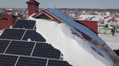 Kışın şiddetli bir kar yağışı sonrasında evin çatısındaki güneş panellerinin hava görüntüsü. Yenilenebilir enerji üretim modülleri